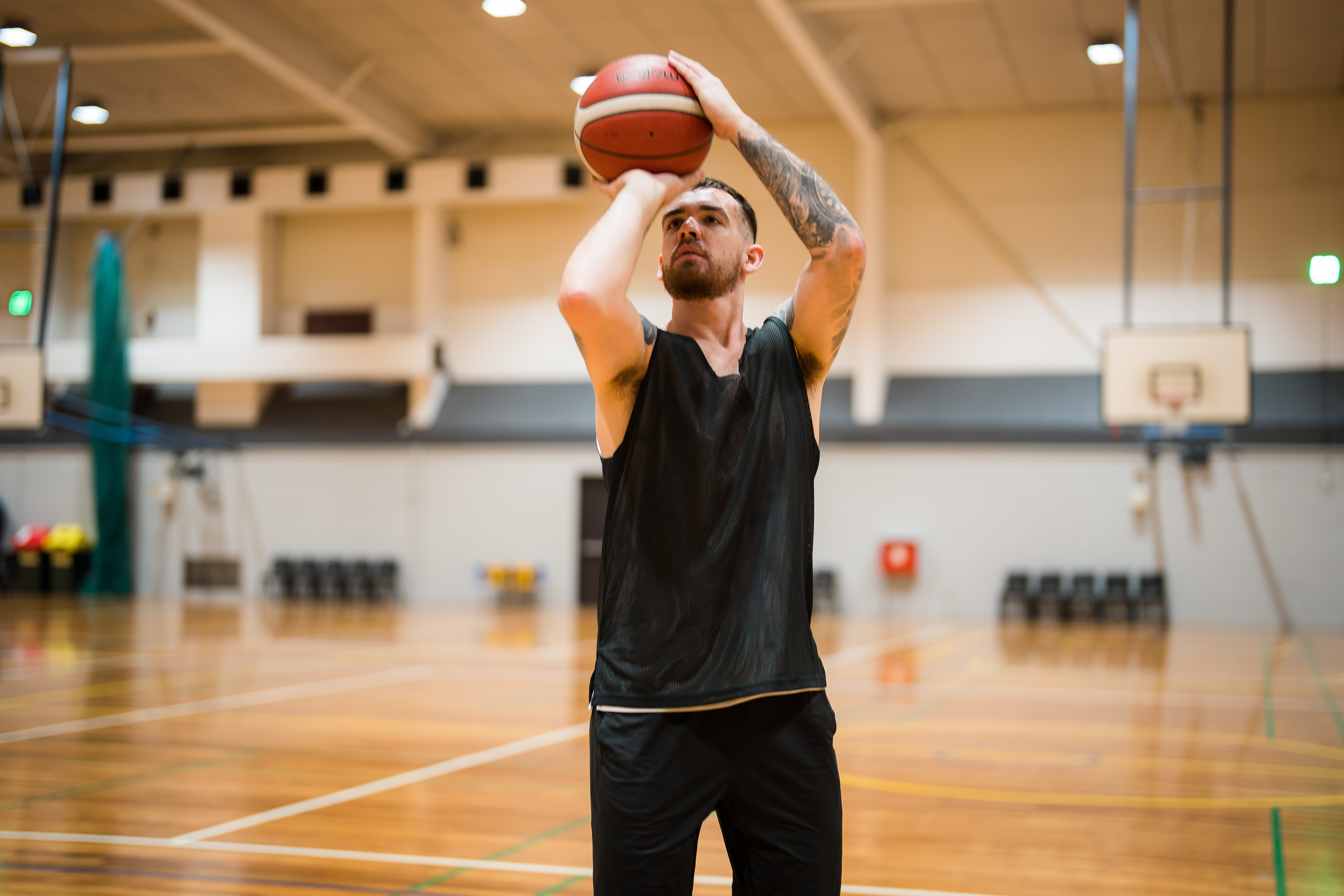 A man holding a basketball about to take a shot in front of a basketball net at Christchurch Recreation and Sport. 