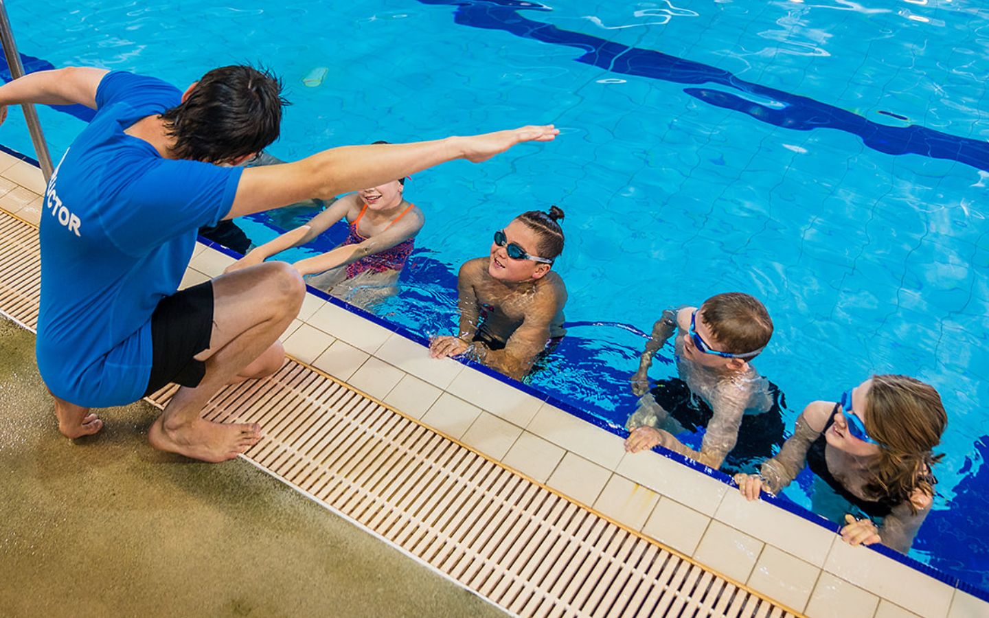 A male swim instructor demonstrating front stroke to a group of children at Christchurch Recreation and Sport pool. 