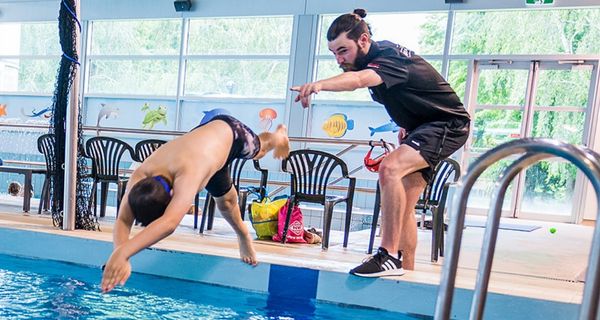 A male swim instructor helping a boy with his diving at Christchurch Recreation and Sport pool. 