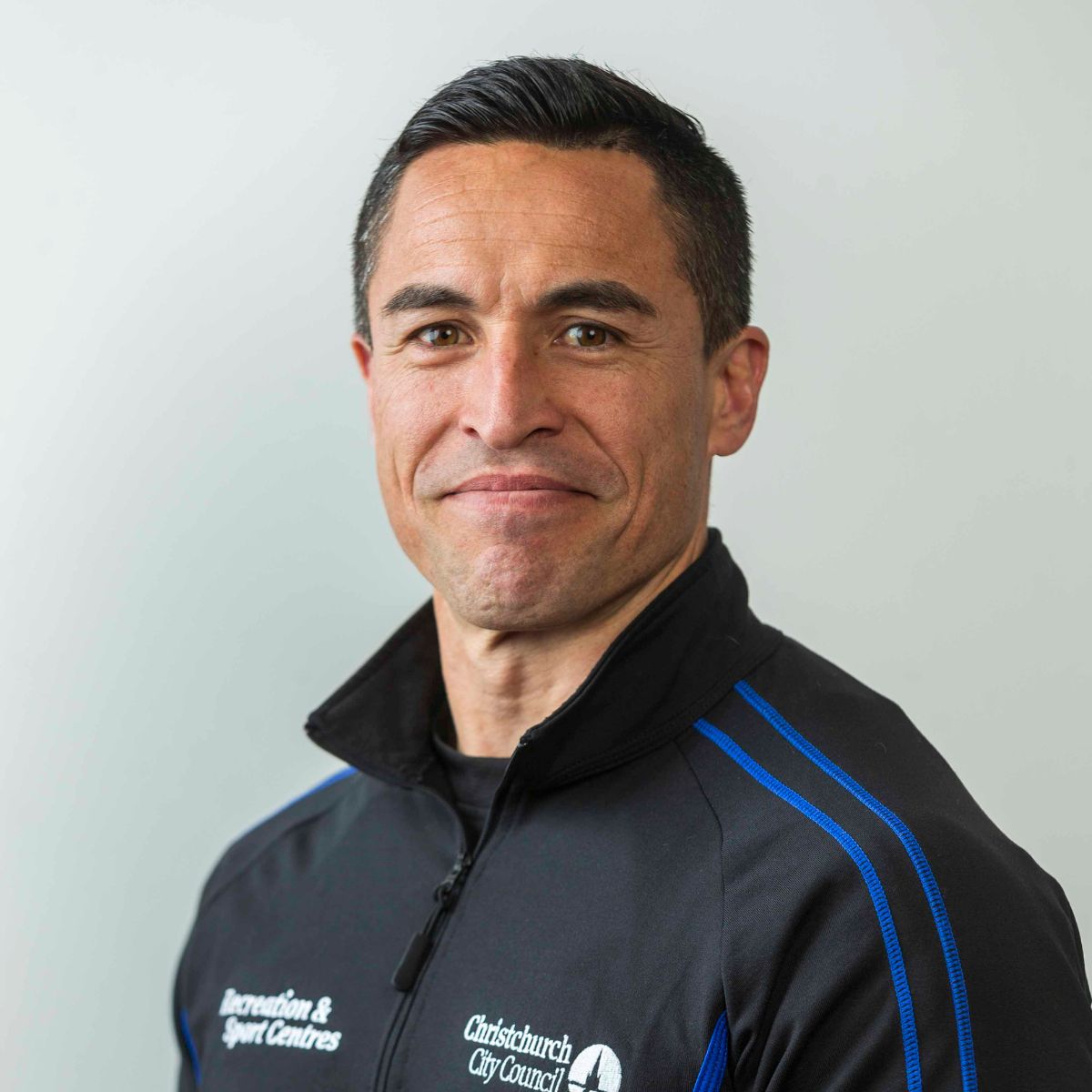 Personal trainer Dan Hibbs smiling wearing a blue and black staff uniform. 