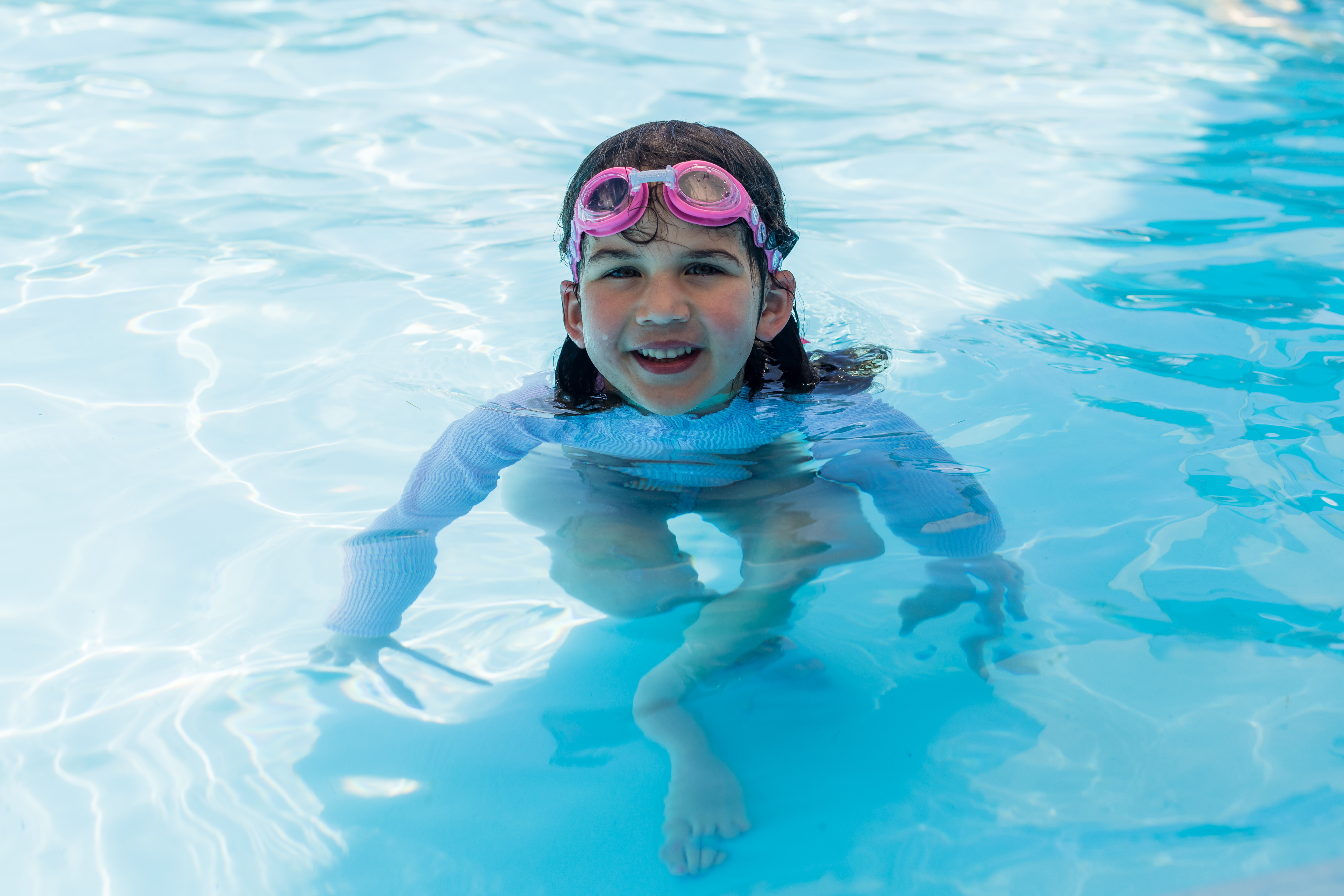 A little girl wearing pink goggles playing in the toddler pool at the Halswell Summer pool. 