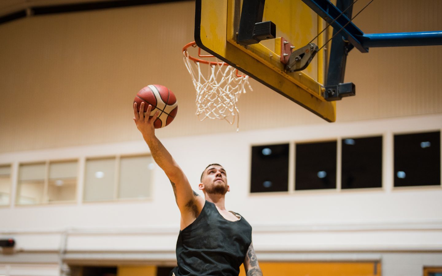 A man jumping and taking a shot into a basketball net at Christchurch Recreation and Sport. 