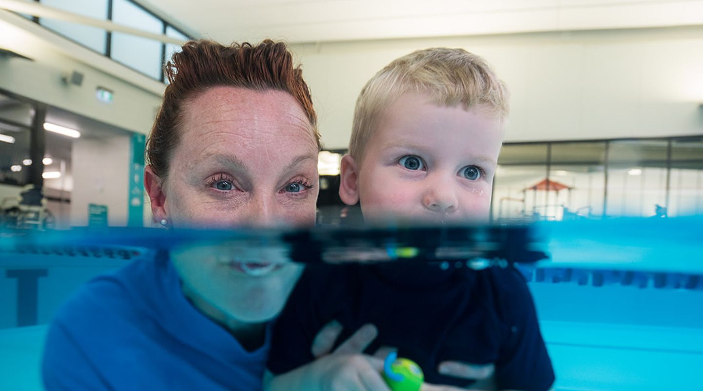 A little boy and a female swim instructor practicing holding their breath at Christchurch Recreation and Sport pool. 