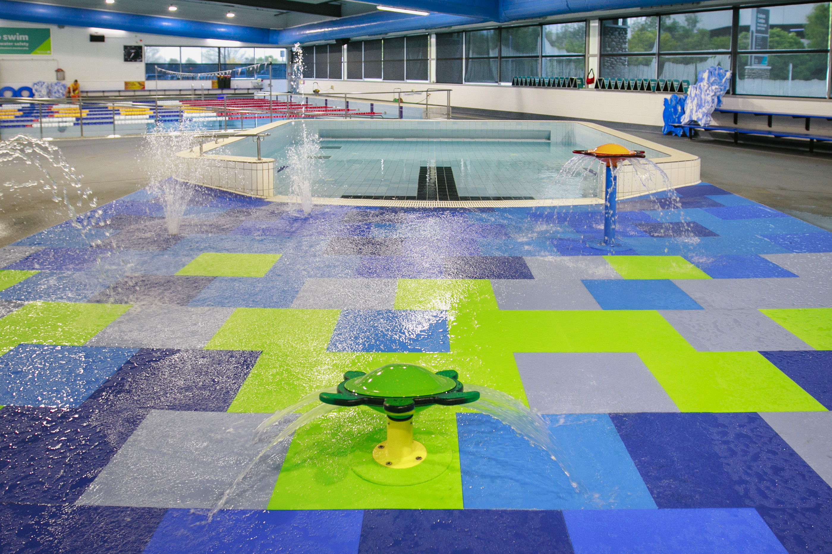 The brightly coloured splash pad decorated with blue and green floor tiles and turtle water features at Graham Condon Recreation centre.