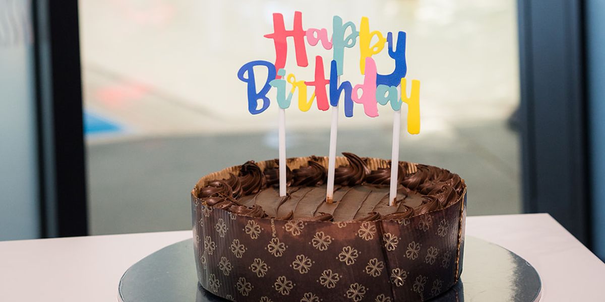 A chocolate birthday cake with a "happy birthday" cake topper. 