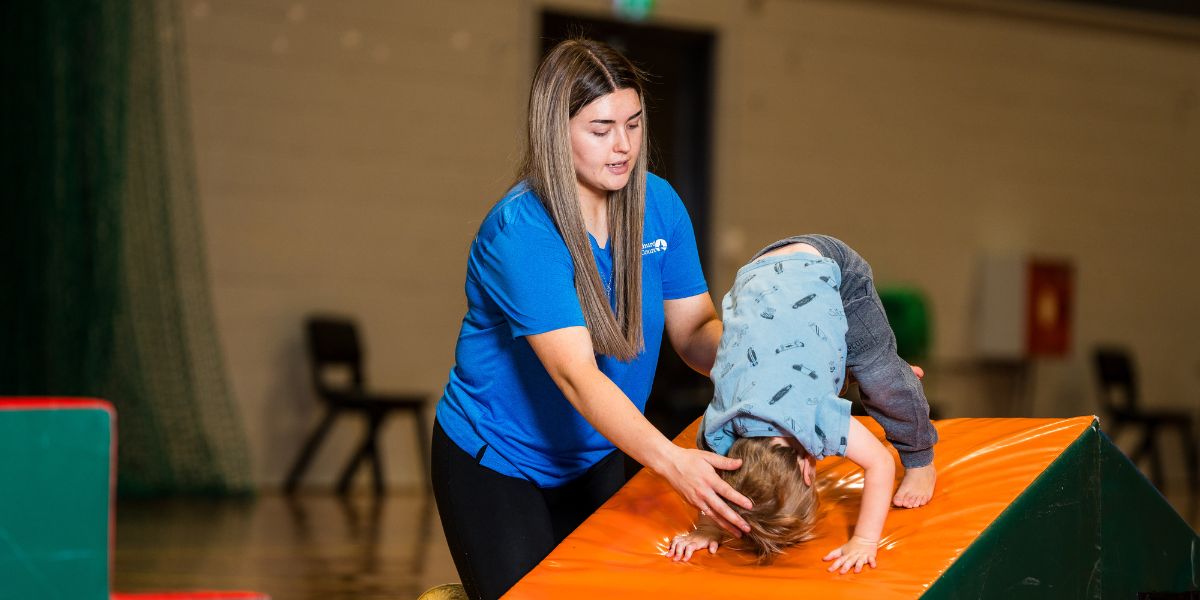 An instructor helping a child with their summersault during a pre-school gymnastics class at Christchurch Recreation and Sport centre. 