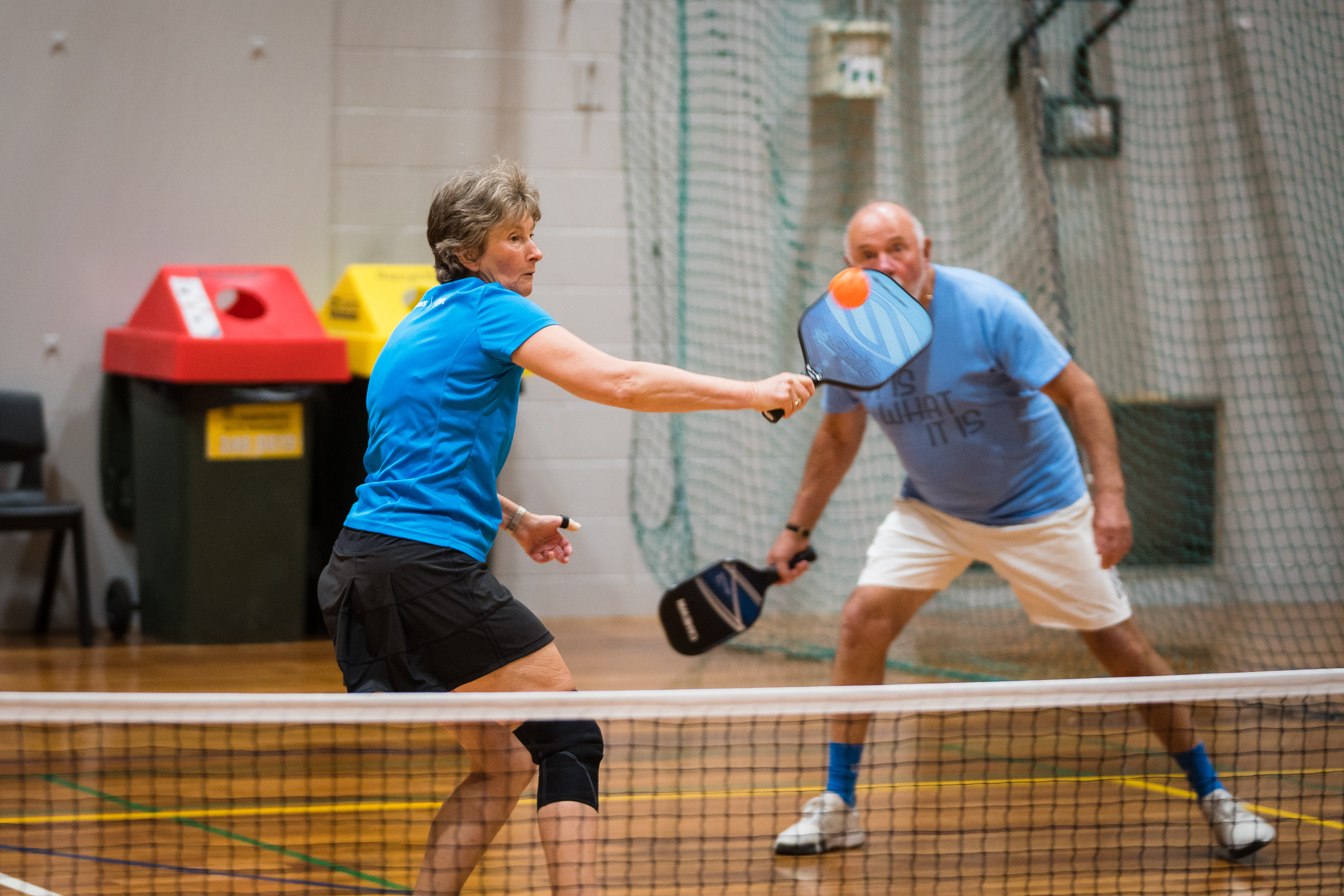 A woman wearing blue hitting an orange ball while playing pickleball at Christchurch Recreation and Sport centre. 