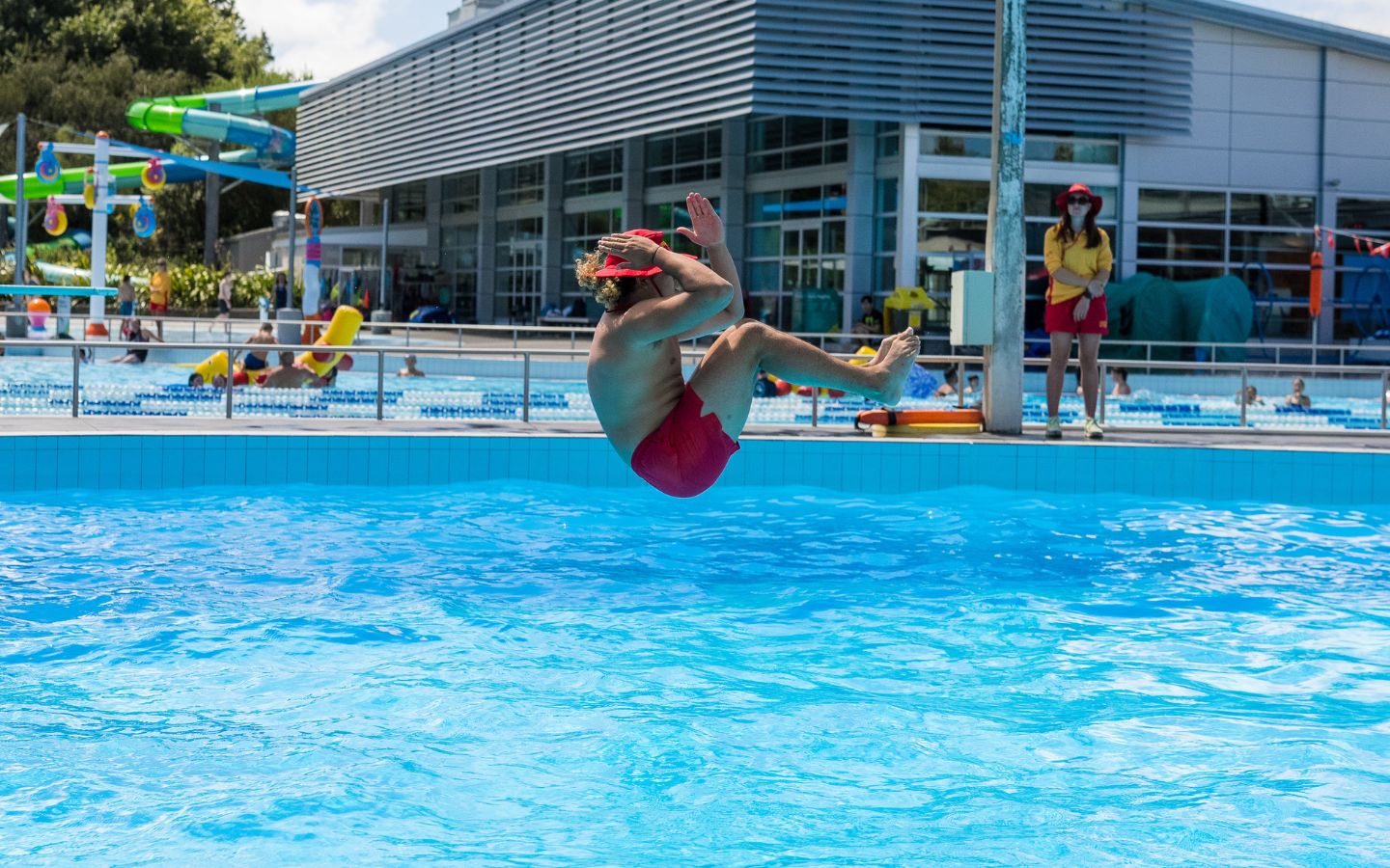 A teenage boy doing a manu off a diving board at Christchurch Recreation and Sport summer pool. 